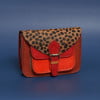 orange leather square satchel handbag with front pocket and tan and blak spotty print hair on hide flap